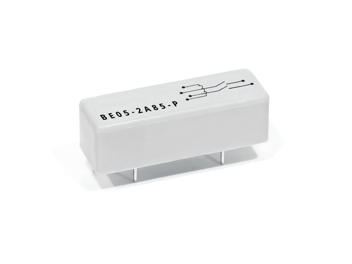 A small, rectangular, white BE Series Reed Relay featuring four metal pins on the bottom, a black circuit diagram, and the label BE05-2A85-P printed on the top surface. by Standex Detect