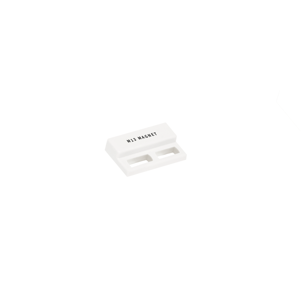 A small, white rectangular object labeled M13 MAGNET with two parallel slots on the front, isolated on a white background. by Standex Detect
